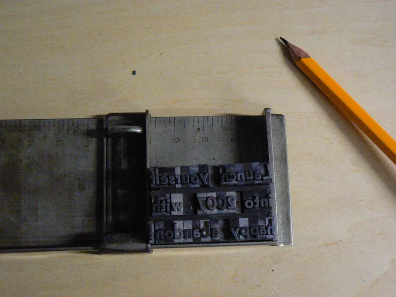 A hand setting metal type in a letterpress composing stick
