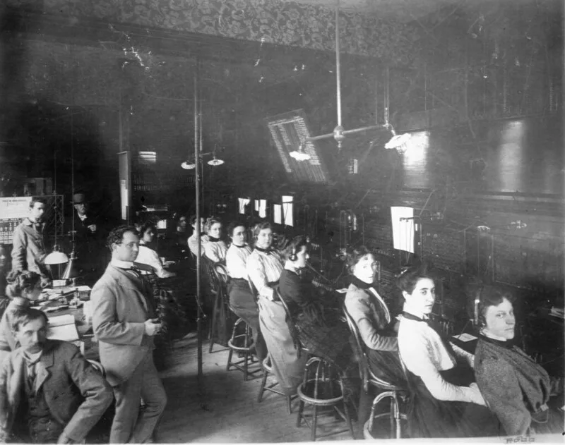 A vintage telephone switchboard with an operator connecting calls