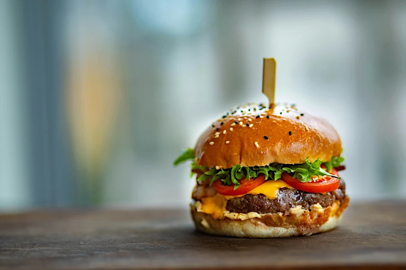 Slow Food for Fast Thinking — a close-up of a gourmet cheeseburger on a wooden surface.
